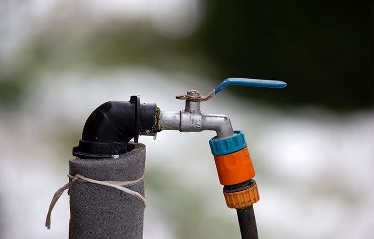 Outdoor water faucet with a hose attachment.