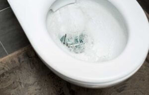 Clean white toilet bowl with flushing money in modern restroom