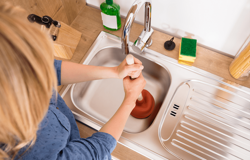 A woman is washing food in the sink.