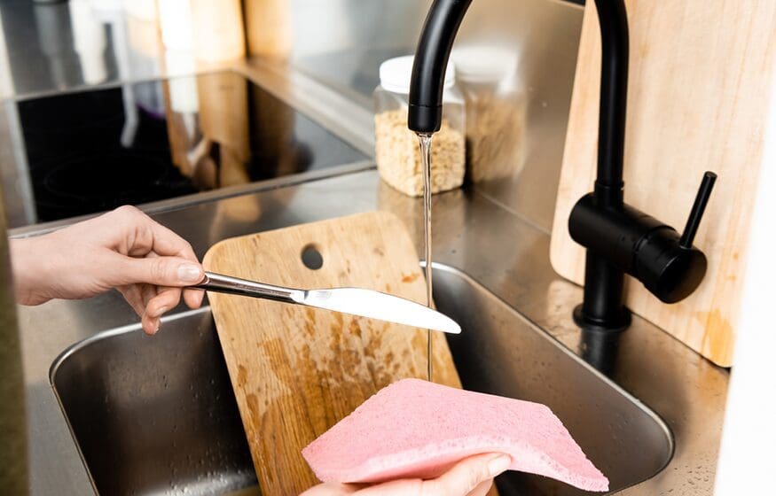 A person cutting up some food in the sink